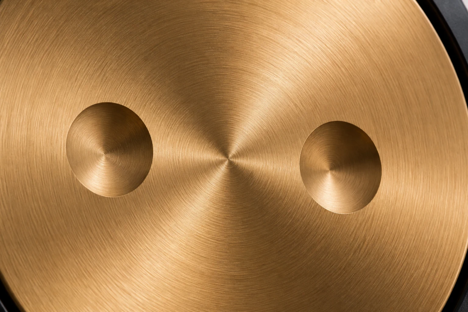 Close-up of the brushed brass gong face, showing the radial machining grain
